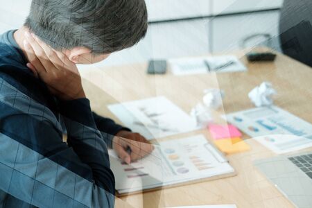 man feeling tired, frustrated & stressed from hard work with crumpled crushed paper on desk. exhausted freelancer have headache at workplace.の写真素材