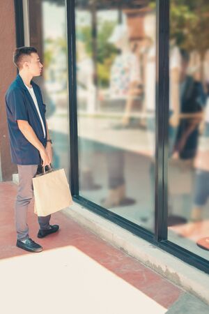 man holding shopping bags looking at shop store windowの写真素材