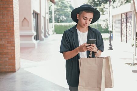 man holding paper shopping bags & using mobile smart phone. consumerism lifestyleの写真素材