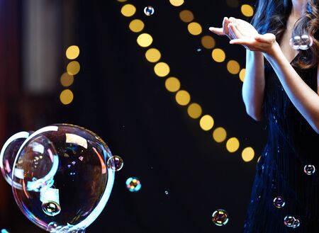 woman in black evening dress with bubble & yellow bokehの写真素材