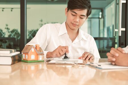 real estate agent using stamper for stamping approved on mortgage loan contract agreement documentの写真素材