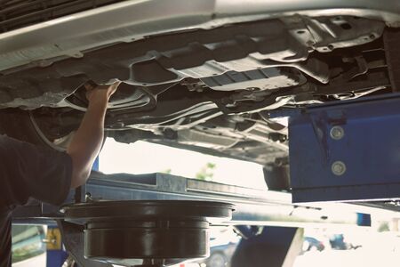 vehicle lift up by hydraulic for motor oil change and transmission inspection. changing  engine oil in automobile repair service. maintenance and checkup in car workshop.の写真素材