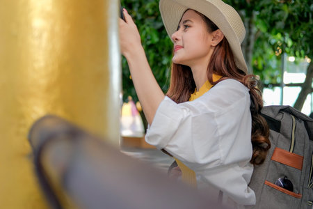 young asian woman traveler tourist knocking bell in temple. journey trip travel concept
