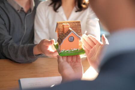 lawyer insurance broker giving house model to couple customer. realtor selling real estate property. buying renting home concept. financial advisor with mortgage loan investment contract.の写真素材