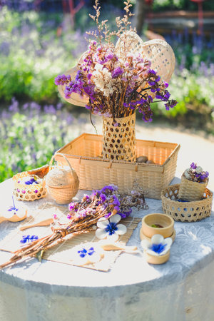 purple flower, candle & wicker basket decorating on table in garden