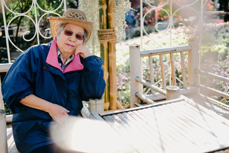 old elder woman resting in garden. asian elderly female relaxing outdoors. senior leisure lifestyle