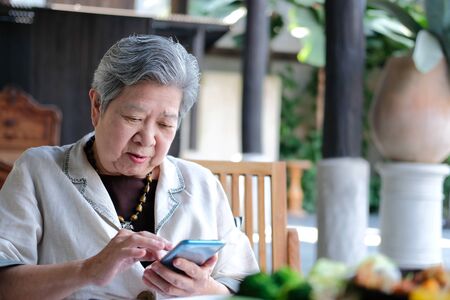 asian elder senior woman using mobile smart phone. elderly female holding cellphone. mature retirement lifestyleの写真素材