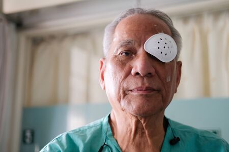 patient covering eye with protective shield & medical plaster after eyes cataract surgery in hospitalの写真素材