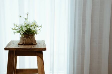 plant pot on wooden bar stool chair beside see through sheer window curtainの写真素材