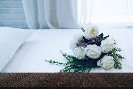 white bridal wedding rose flower bouquet on bed beside see through sheer window curtainの写真素材