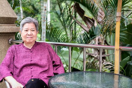asian elder female woman resting relaxing on balcony terrace. elderly senior leisure lifestyleの写真素材