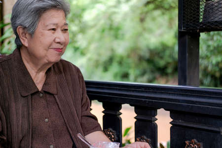 asian elder female woman resting relaxing on balcony terrace at home. elderly senior leisure lifestyleの写真素材
