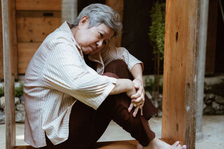 stressed depressed fatigued sad upset asian old asian elderly senior elder woman sitting at homeの写真素材