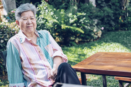 elder woman resting in garden. asian elderly female relaxing outdoors. senior leisure lifestyle