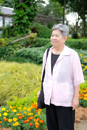 asian old elderly female elder woman resting relaxing in garden. senior leisure lifestyleの写真素材