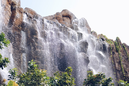 manmade waterfall park. flowing water stream in gardenの写真素材