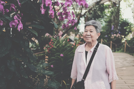 asian old elderly female elder woman resting relaxing in garden. senior leisure lifestyleの写真素材