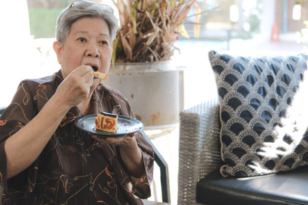 old asian elderly senior elder woman eating cheesecake at home restaurant. senior retirement...