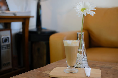 artificial white gerbera flower with hot latte cappuccino mocha coffee on table at home