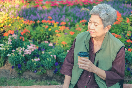 asian old elderly female elder woman drinking coffee tea in garden. senior leisure lifestyleの写真素材