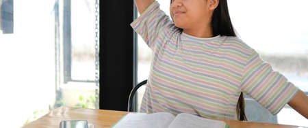 asian girl student stretching while reading book feeling tired bored sleepy. children educationの写真素材