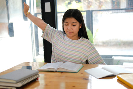 asian girl student stretching while reading book feeling tired bored sleepy. children education