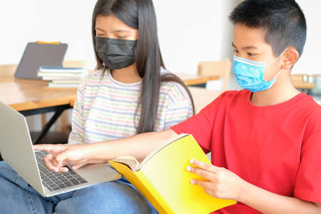 asian boy girl student wearing face mask studying learning lesson online. remote meeting distance education at homeの写真素材