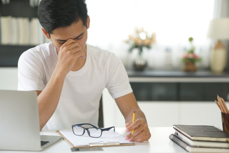 asian young teenage student man teenager entrepreneur studying working hard feeling stressed tired exhausted bored. work education at homeの写真素材