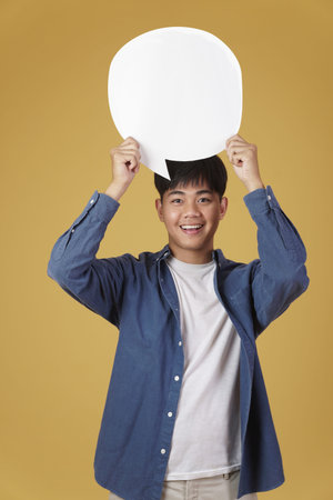 portrait of smiling happy cheerful young asian man dressed casually with empty speech bubble...