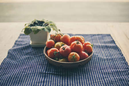 fresh raw red tomatoes in basket on tableの写真素材