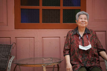 asian old elder woman elderly female relaxing resting on balcony terrace. senior leisure lifestyleの写真素材
