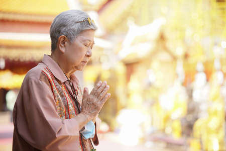 old asian elder senior woman traveler tourist praying at buddhist temple.の写真素材