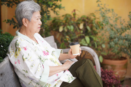 old elderly senior elder woman drinking hot coffee in garden. mature retirement lifestyle