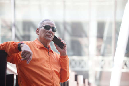 asian old elder senior man elderly talking on mobile smart phone cellphone outdoor. mature retirement lifestyleの写真素材