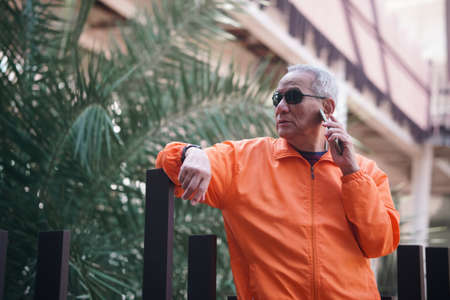 asian old elder senior man elderly talking on mobile smart phone cellphone outdoor. mature retirement lifestyleの写真素材