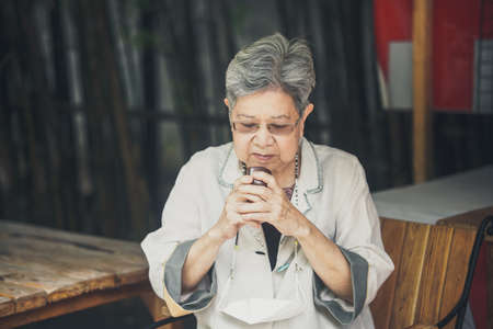 asian old elderly female elder woman drinking hot tea in garden. senior leisure lifestyleの写真素材