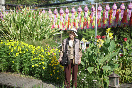 old elderly elder senior woman resting relaxing walking in flower gardenの写真素材
