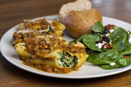 A meal of stuffed shells with meat sauce and a side salad with breadの写真素材