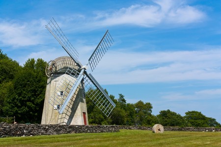 Historic New England windmill behind a stone fence and in a grassy fieldの写真素材