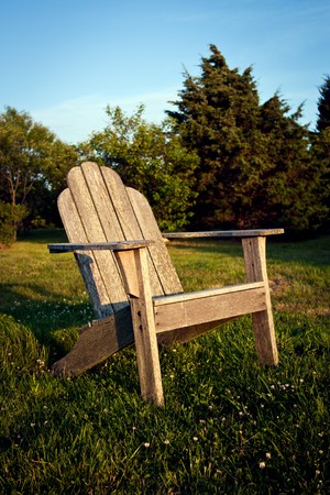 Empty chair in a meadow facing the sunsetの写真素材