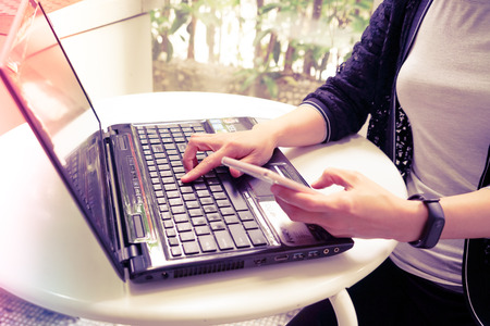 Young student women using laptop computer and holding smart phoneの写真素材