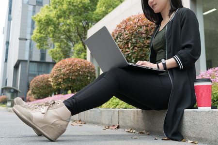 A pretty student woman is using laptop computerの写真素材