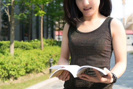 A young student woman is reading a book on handの写真素材