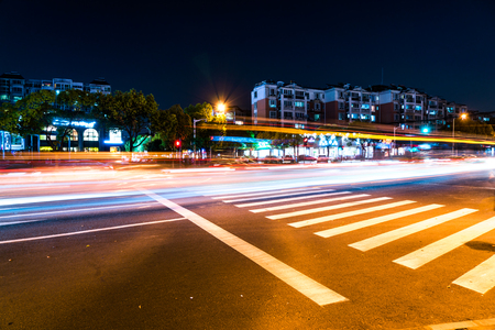 Fast moving traffic with the red and golden light on the crosswalk roadの写真素材