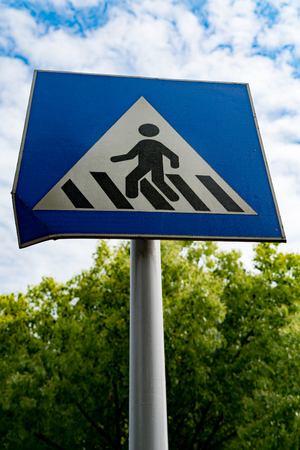 pedestrian sign or crosswalk sign with blue sky and green treeの写真素材