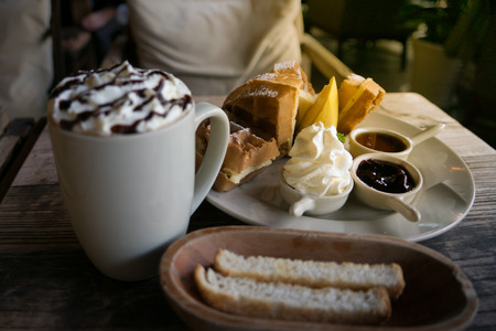 A plate of waffle with banana, whipping cream, blueberry and syrup, delicious, yummyの写真素材