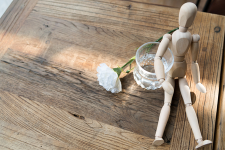 a wood man is sitting and put the arm on the glass of waterの写真素材