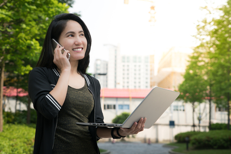 A woman is on call and holding laptop computerの写真素材
