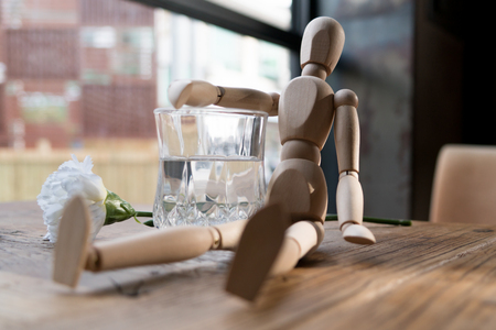 a wood man is sitting and put the arm on the glass of waterの写真素材