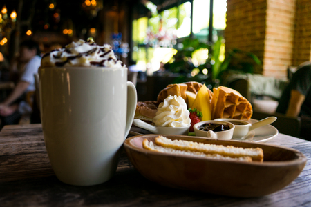 A plate of waffle with banana and strawberry, whipping cream, blueberry and syrup, delicious, yummyの写真素材